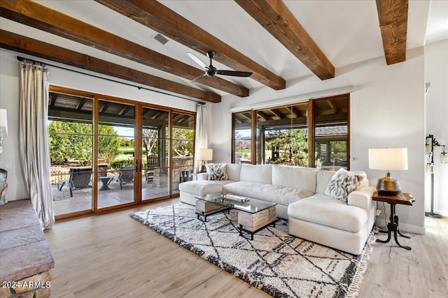 living room with light wood-style flooring, beamed ceiling, visible vents, ceiling fan, and baseboards