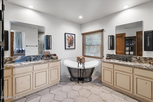 bathroom with tile patterned floors, two vanities, tile walls, a freestanding tub, and a sink