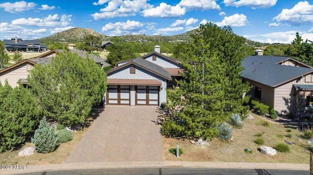 view of front of house with decorative driveway, a mountain view, and a garage