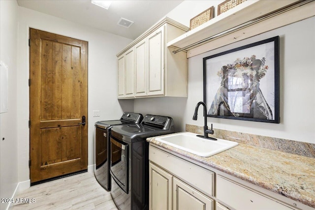 laundry room with a sink, cabinet space, light wood-style floors, washing machine and dryer, and visible vents