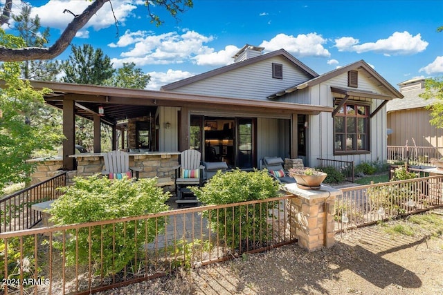 rear view of property featuring covered porch, fence private yard, board and batten siding, and a chimney