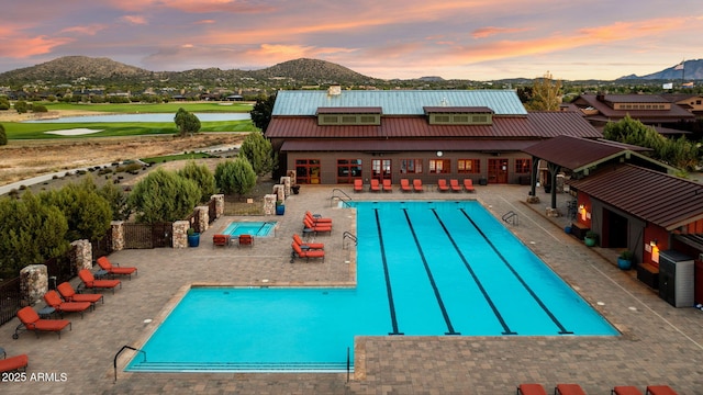 community pool featuring view of golf course, a water and mountain view, and a patio area