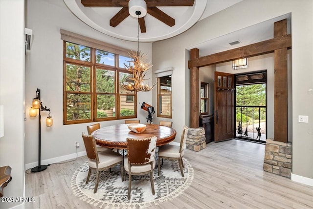 dining space with light wood finished floors, baseboards, plenty of natural light, and ceiling fan with notable chandelier