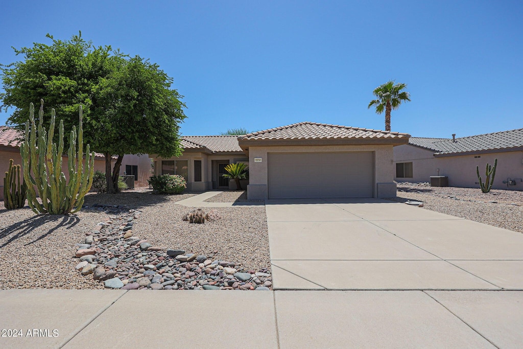 view of front of property with a garage, a tile roof, concrete driveway, and stucco siding