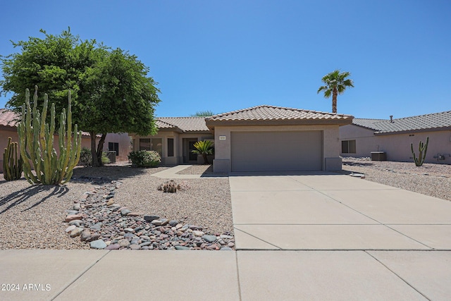 view of front of property with a garage, a tile roof, concrete driveway, and stucco siding