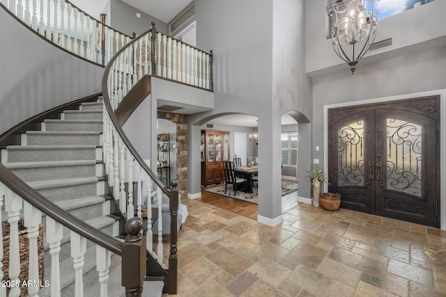 9708 E Pampa Ave, Mesa, AZ 85212 - entryway with arched walkways, stone tile flooring, a high ceiling, a chandelier, and french doors
