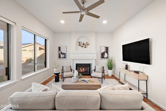 living room featuring ceiling fan, a large fireplace, and light hardwood / wood-style floors