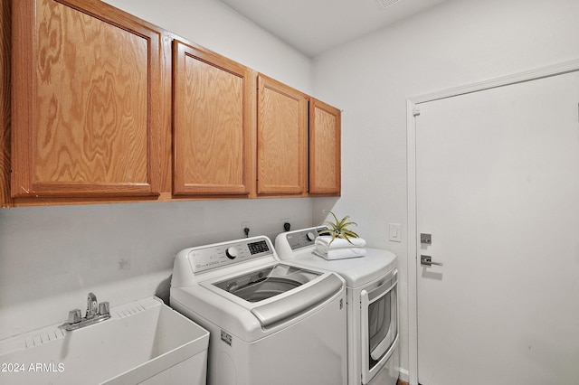 washroom with washer and dryer, sink, and cabinets