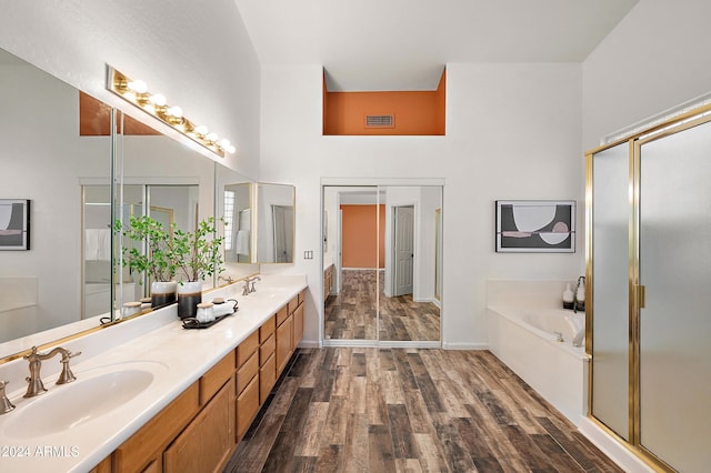 bathroom featuring hardwood / wood-style flooring, vanity, separate shower and tub, and a towering ceiling