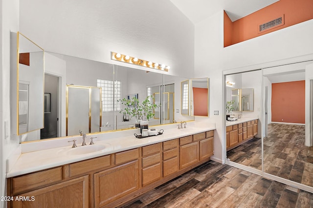 bathroom with a towering ceiling, vanity, hardwood / wood-style flooring, and walk in shower