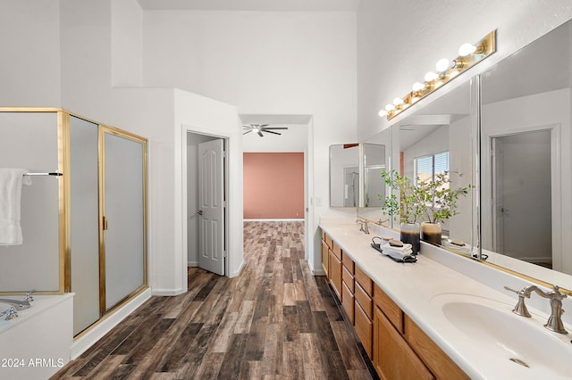 bathroom featuring ceiling fan, a high ceiling, hardwood / wood-style floors, a shower with door, and vanity