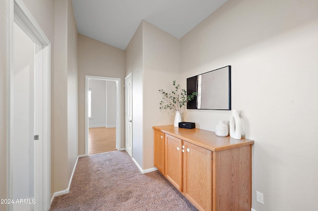 corridor with light colored carpet and vaulted ceiling