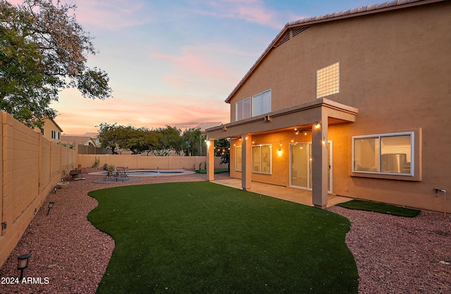 yard at dusk with a fenced in pool and a patio