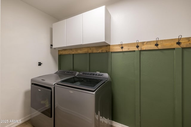 laundry room with cabinet space, baseboards, and washer and clothes dryer
