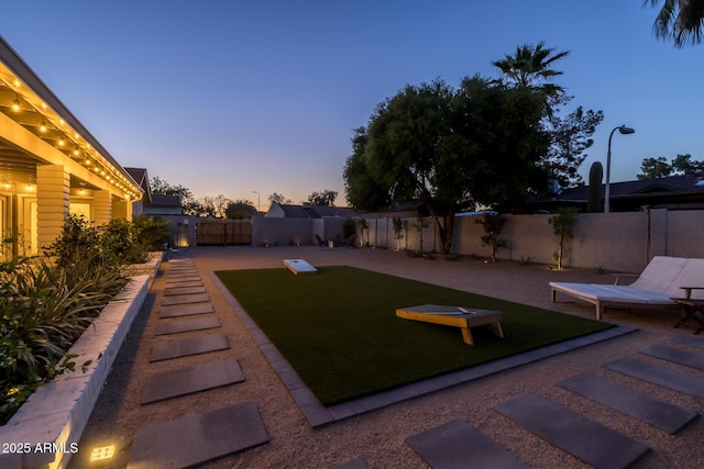 yard at dusk featuring a fenced backyard and a patio area
