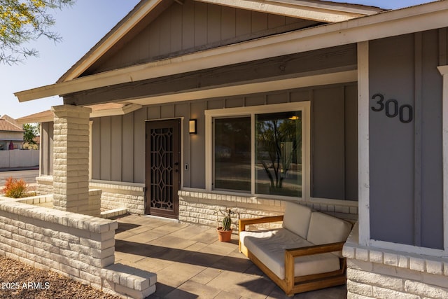 view of exterior entry with a porch and board and batten siding
