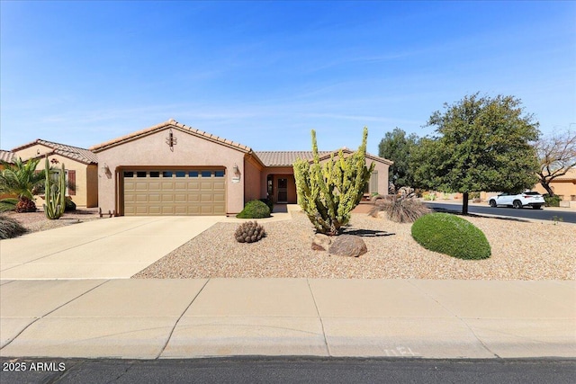 mediterranean / spanish house with concrete driveway, a tile roof, an attached garage, and stucco siding