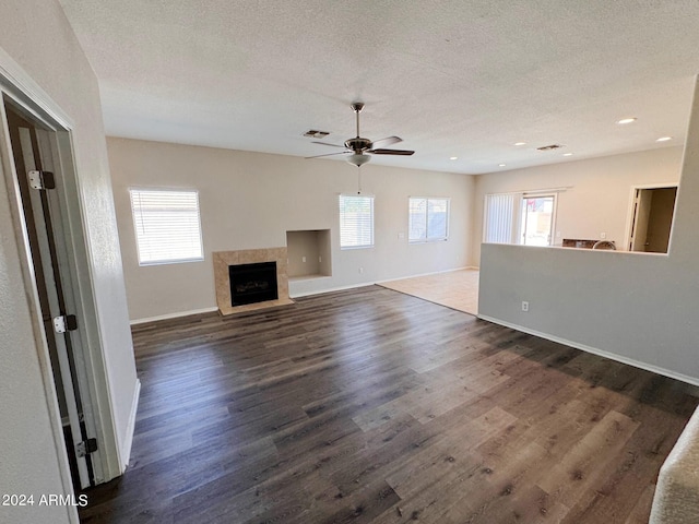 unfurnished living room featuring dark wood-type flooring, ceiling fan, a premium fireplace, and a textured ceiling