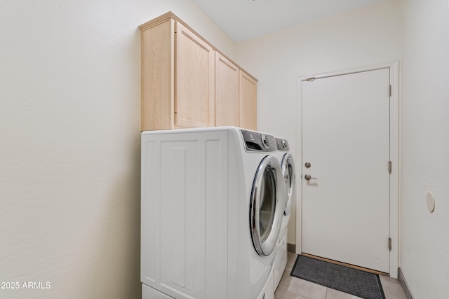 laundry room featuring cabinets, light tile patterned floors, and washer and dryer