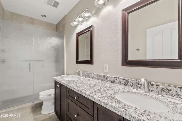 bathroom with a shower with door, vanity, tile patterned floors, and toilet