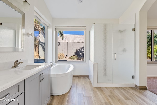 bathroom with wood-type flooring, separate shower and tub, vaulted ceiling, and vanity