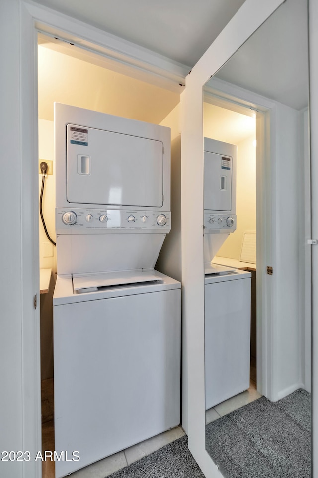 washroom featuring stacked washing maching and dryer and light tile patterned flooring