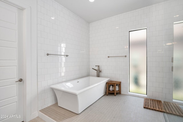 bathroom featuring tile walls, a bath, and tile patterned flooring