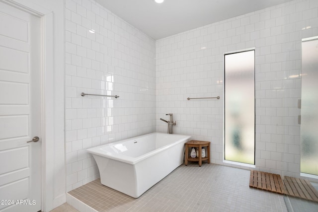 full bath with tile patterned flooring, a freestanding tub, and tile walls