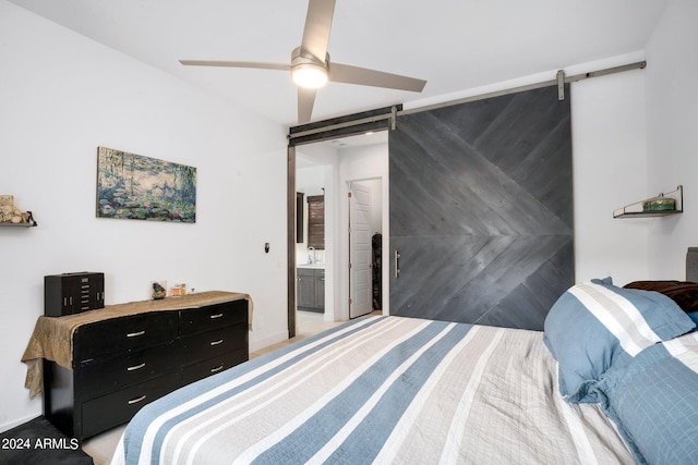 bedroom with ceiling fan, a barn door, and connected bathroom