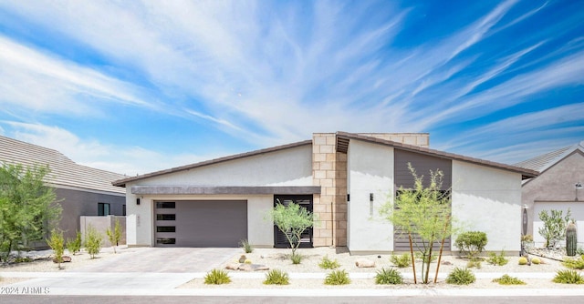 view of front facade with stucco siding, an attached garage, and driveway