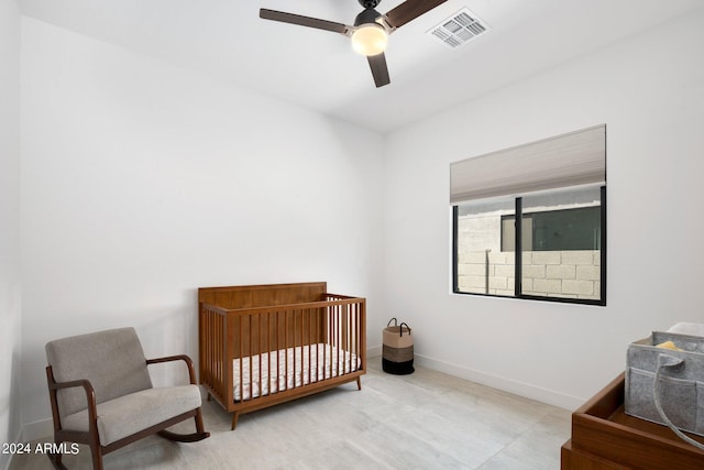 bedroom with visible vents, a ceiling fan, baseboards, and a crib