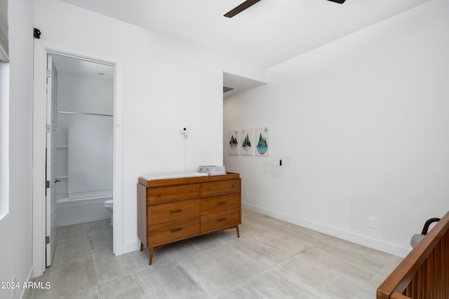 bedroom featuring a closet, baseboards, a walk in closet, ceiling fan, and light tile patterned floors