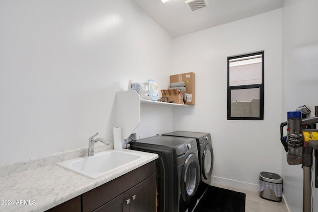 washroom with cabinets, washer and dryer, and sink