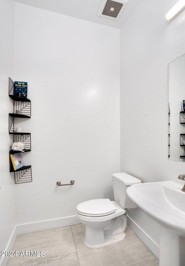 half bath with visible vents, baseboards, tile patterned floors, and toilet