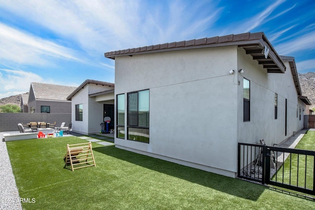 rear view of house featuring fence private yard, a patio, stucco siding, an outdoor hangout area, and a lawn