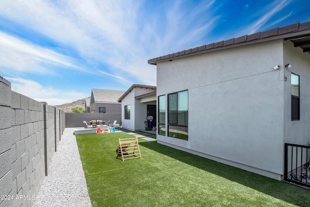 rear view of property with a lawn, a fenced backyard, a patio area, and stucco siding