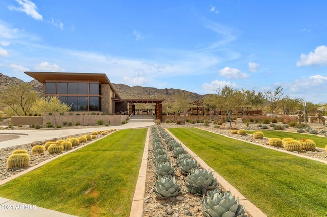 back of house with a mountain view and a yard