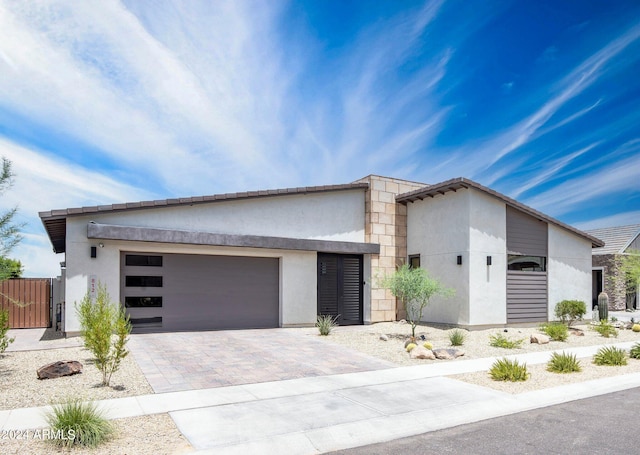 contemporary house featuring a garage, fence, stucco siding, a gate, and driveway