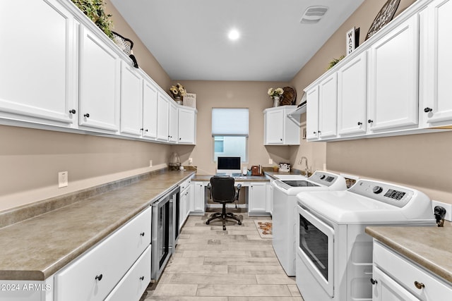 laundry area with light hardwood / wood-style floors, cabinets, sink, washing machine and dryer, and wine cooler