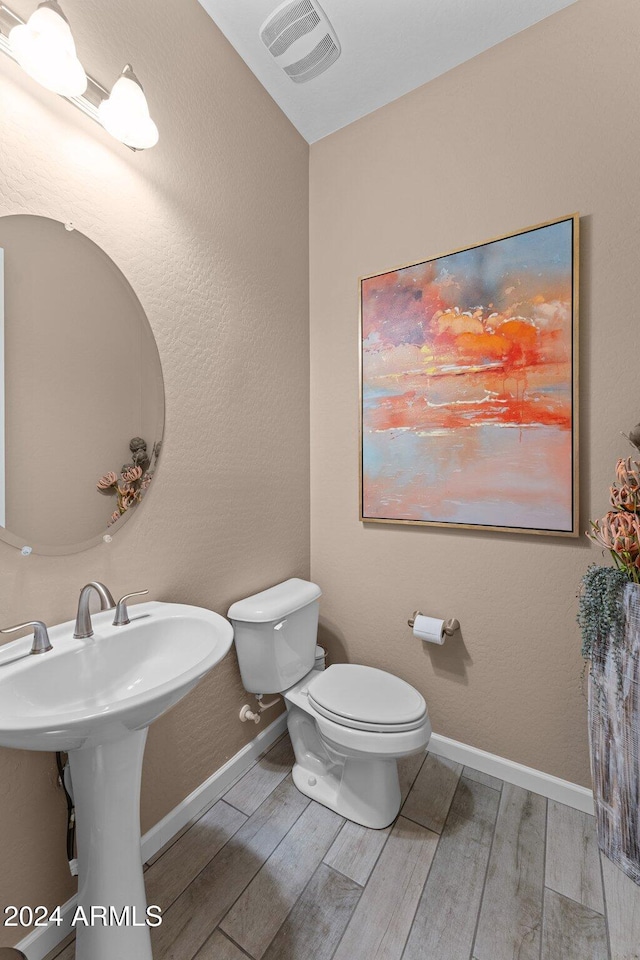 bathroom featuring toilet and wood-type flooring