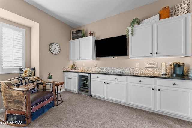 bar with white cabinets, light colored carpet, and beverage cooler