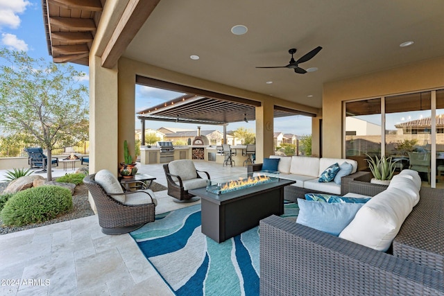 view of patio / terrace with ceiling fan, grilling area, an outdoor living space with a fire pit, and exterior kitchen