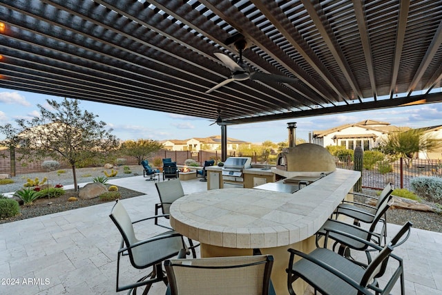 view of patio with ceiling fan, an outdoor kitchen, a bar, and grilling area