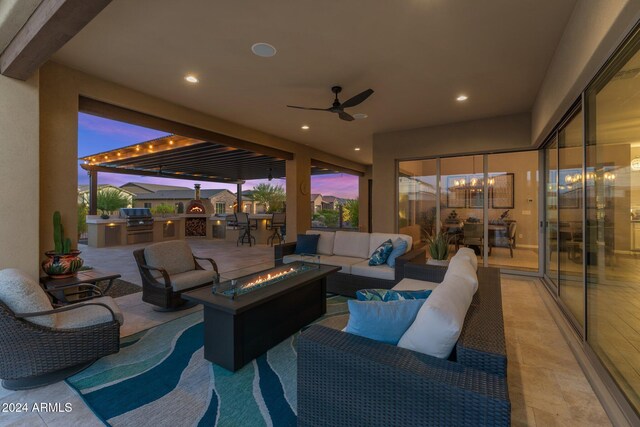 patio terrace at dusk featuring an outdoor kitchen, an outdoor living space with a fire pit, and area for grilling