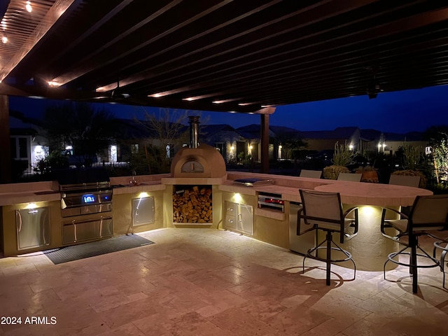 patio at twilight featuring an outdoor wet bar and area for grilling