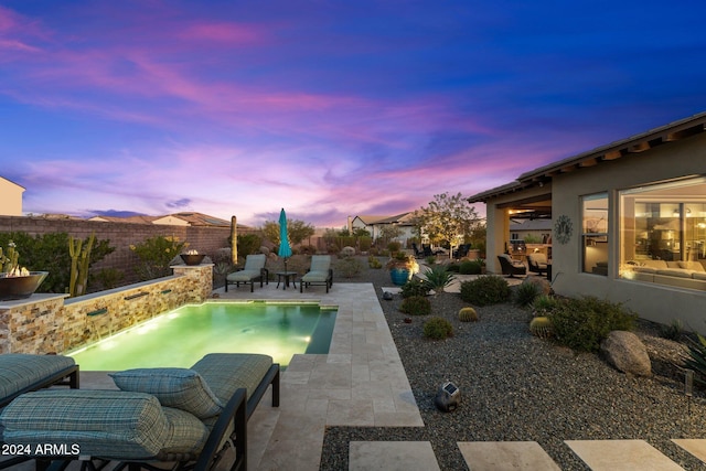 pool at dusk with a patio area