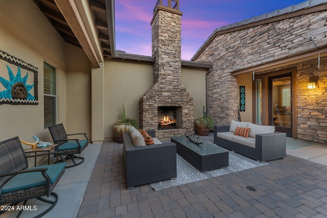 patio terrace at dusk featuring an outdoor living space with a fireplace