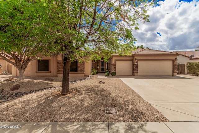 view of front of house with stucco siding, driveway, stone siding, a garage, and a tiled roof