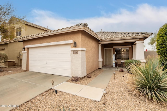 mediterranean / spanish home featuring a garage, concrete driveway, a tile roof, and stucco siding