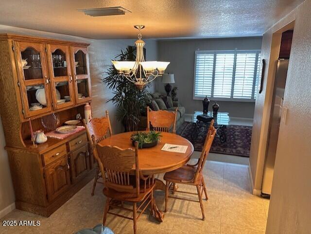 dining space with a notable chandelier and a textured ceiling